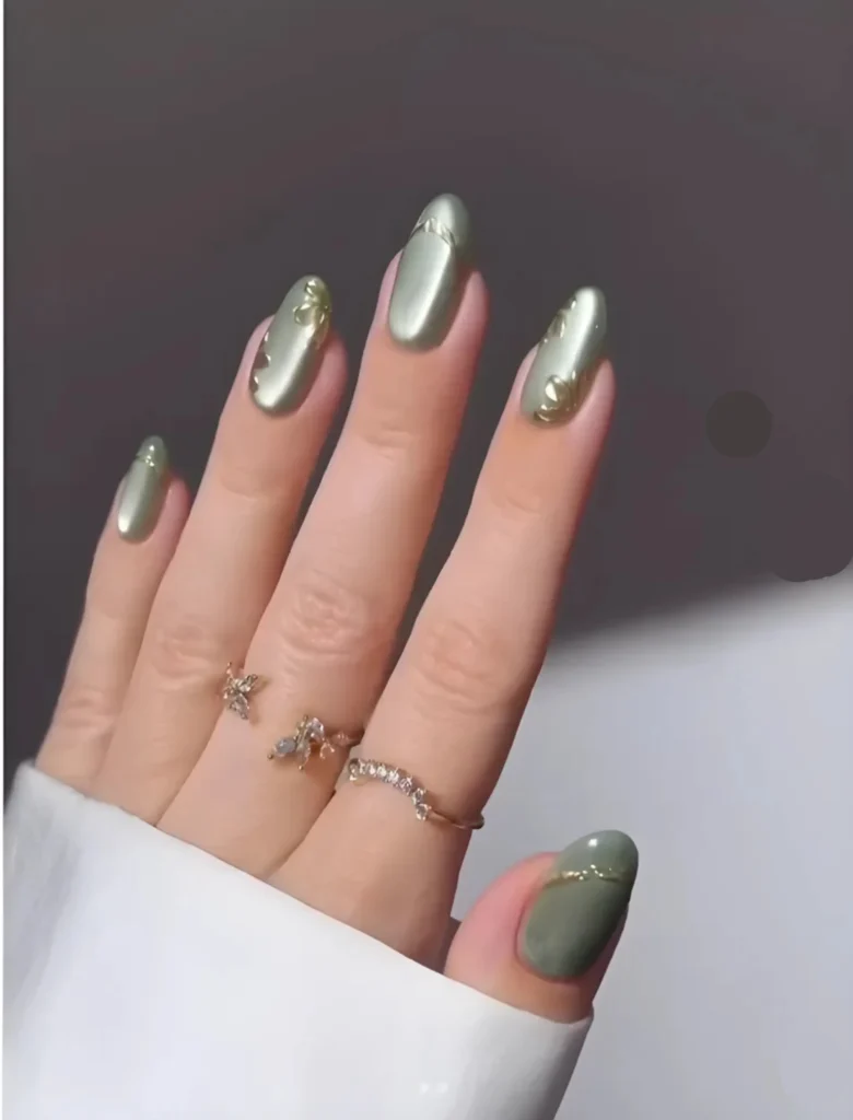Stylish green and silver nail art with a glossy finish, featuring rings on the fingers. A trendy and subtle design for a modern, polished appearance