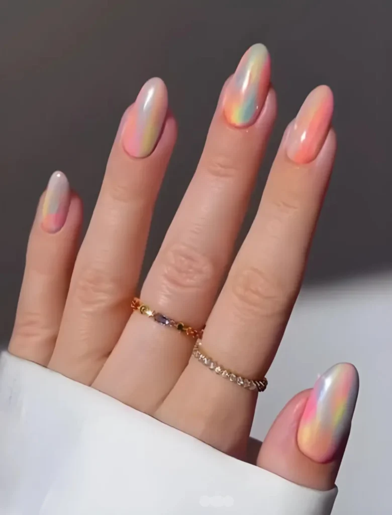 Nude nail art with a shiny ombre effect, complemented by minimalistic rings. A sleek and sophisticated design for an effortlessly chic appearance