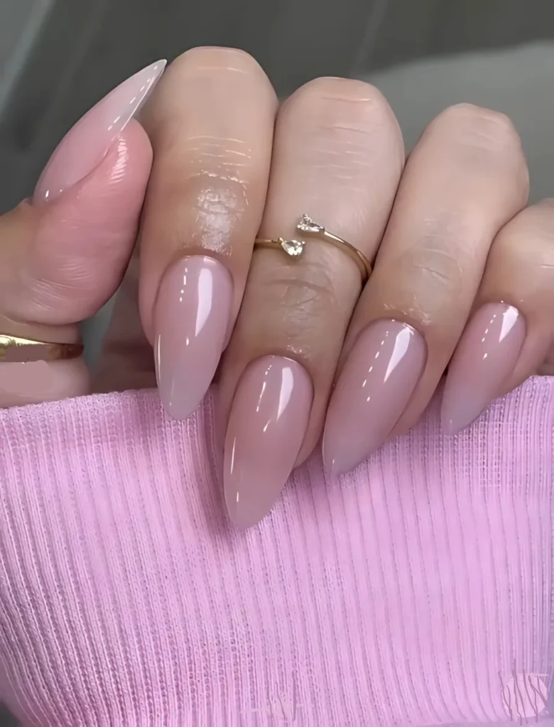 Soft nude pink nail art with a sleek finish and minimalistic rings