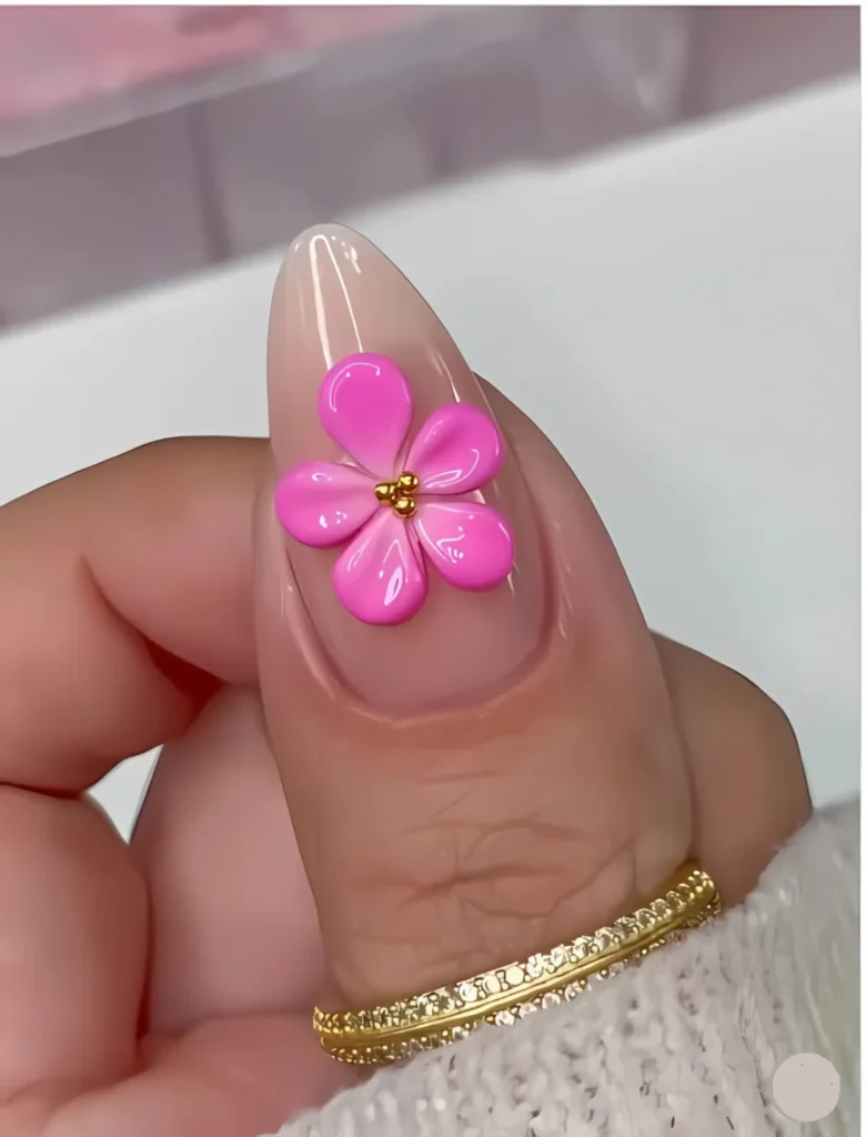 Bright pink floral nail art with a vibrant flower accent and delicate gold rings. A playful yet elegant design for those seeking unique and eye-catching nails